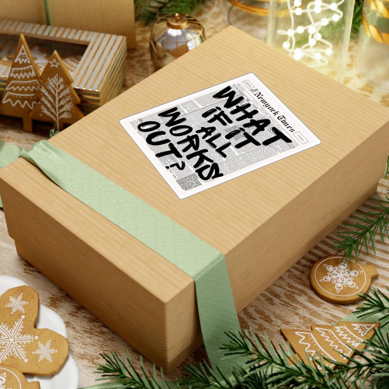 May include: A rectangular gift box wrapped in light brown paper and tied with a light green ribbon. A sticker on top reads "WHAT IF IT ALL WORKS OUT?" in bold black letters, with "The New York Times" printed above. The scene includes holiday decorations.