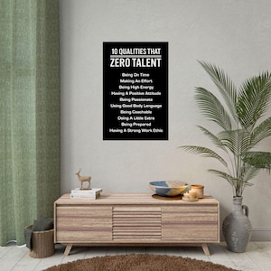 May include: A black and white poster with the text "10 QUALITIES THAT ZERO TALENT" and a list of ten qualities. The poster is displayed on a light wood cabinet with decorative items and a plant.