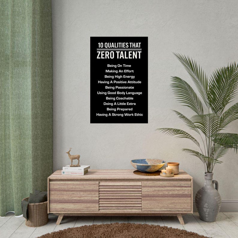 May include: A black and white poster with the text "10 QUALITIES THAT ZERO TALENT" and a list of ten qualities. The poster is displayed on a light wood cabinet with decorative items and a plant.