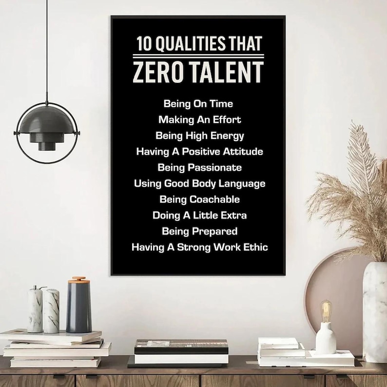 May include: A black poster with white text listing "10 QUALITIES THAT ZERO TALENT" including "Being On Time", "Making An Effort", and "Having A Strong Work Ethic". The poster is displayed on a wooden surface.