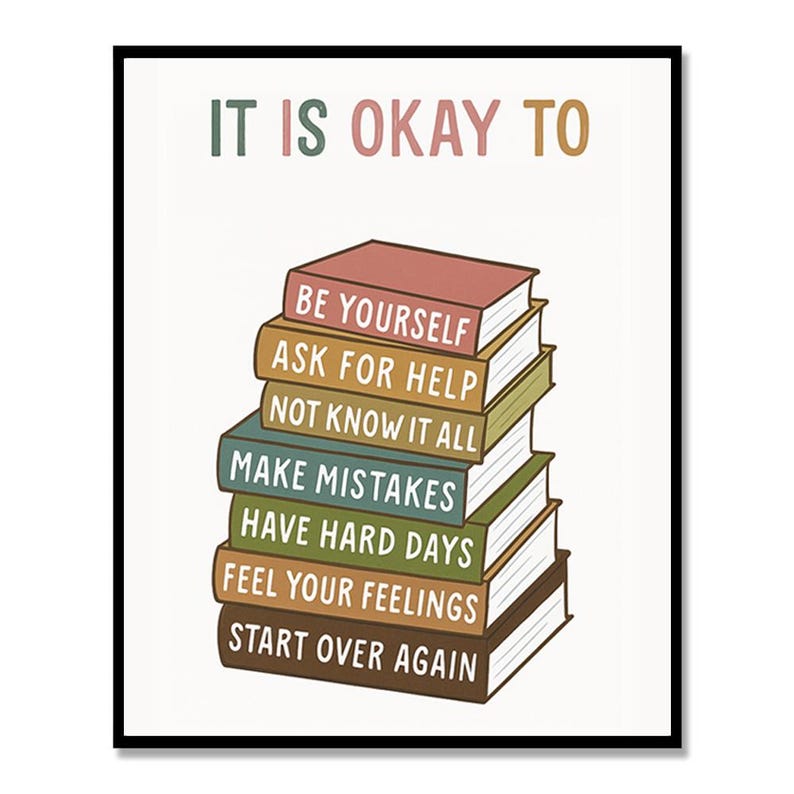 May include: A framed print with the words "IT IS OKAY TO" at the top, above a stack of books. Each book spine has a different phrase, including "BE YOURSELF" and "START OVER AGAIN". The text is in various colors.