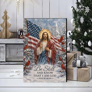 May include: A rectangular wall art print featuring a central figure of Jesus with a golden halo, standing before an American flag in a snowy forest. Red cardinals are perched on pine branches. Text reads: Be Still AND KNOW THAT I AM GOD PSALM 46:10.