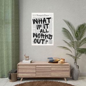 May include: A black and white print of a newspaper page with the headline "WHAT IF IT ALL WORKS OUT?" in bold, handwritten-style lettering. The print is displayed on a wall above a wooden cabinet with decorative items.