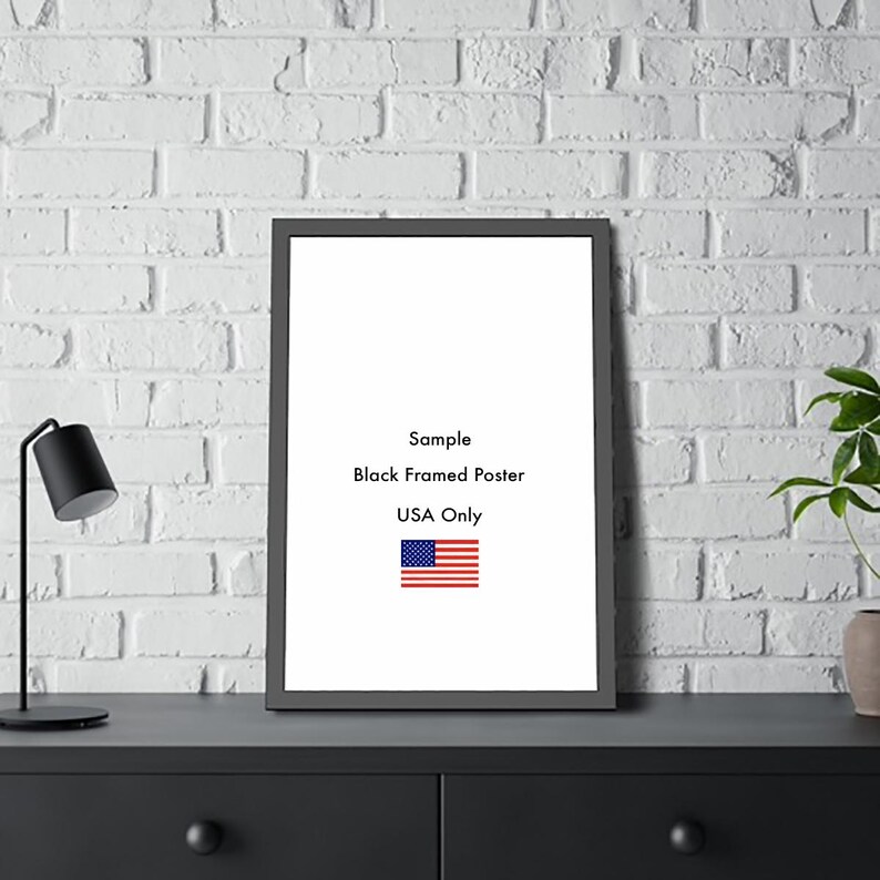 以下が含まれることがあります： 「Sample Black Framed Poster USA Only」のテキストと小さなアメリカ国旗が入った黒いフレームのポスター。 ポスターは、白いレンガの壁を背景に、黒い表面に表示されています。