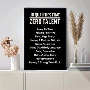May include: A framed black and white print with the text "10 QUALITIES THAT ZERO TALENT" and a list of ten qualities. The print is displayed on a white cabinet with decorative plants.