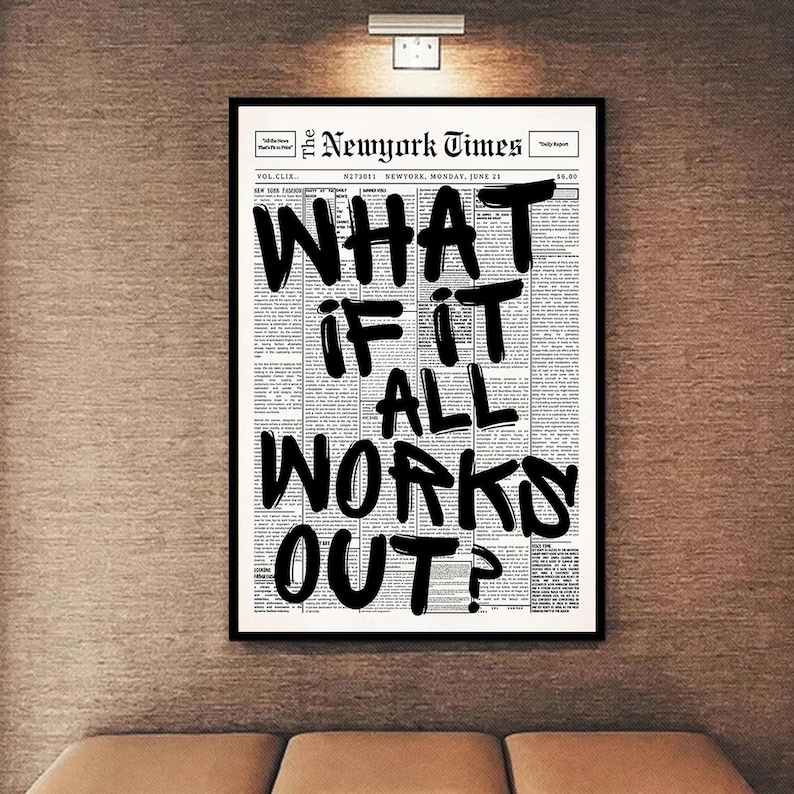 May include: A framed print featuring a black and white newspaper page with the headline "WHAT IF IT ALL WORKS OUT?" in bold, handwritten-style lettering. The print is set against a neutral wall.