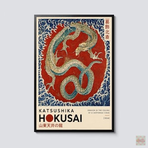May include: A framed art print featuring a coiled dragon in shades of green and blue against a large red circle, surrounded by stylized blue waves. The text reads Katsushika Hokusai, Dragon in the Ceiling of a Shotengai, and 1834.
