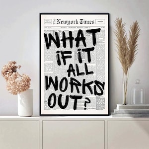 May include: A framed print featuring a newspaper page with the headline "The Newyork Times." Bold black text reads "WHAT IF IT ALL WORKS OUT?" The print is displayed on a white cabinet, with decorative flowers and a vase.