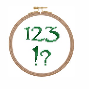 May include: A wooden embroidery hoop with green cross-stitch embroidery that reads "123 1?"