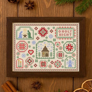 Puede incluir: Un bordado de punto de cruz enmarcado con diseños navideños en rojo, verde y azul. La obra de arte incluye imágenes de un pesebre, copos de nieve, una iglesia y el texto "O Holy Night". El marco es de color marrón oscuro.