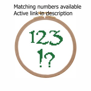 May include: Green cross-stitch embroidery of the numbers 123 and 1? in a wooden embroidery hoop.