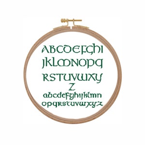 May include: A wooden embroidery hoop with the alphabet in green lettering. The letters are in a traditional font. The letters are in two rows, with the uppercase letters on top and the lowercase letters on the bottom.