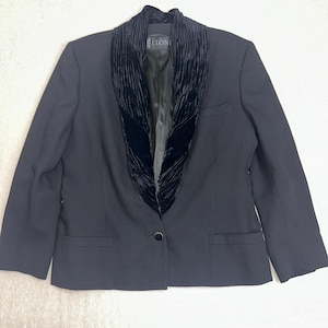 May include: A black blazer with a velvet collar. The blazer has a single-button closure and two front pockets. The label "LEONE" is visible on the collar. The jacket is a classic style.