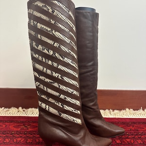 May include: A set of three ceramic mugs with a speckled, cream-colored glaze. Each mug features a different hand-painted floral design in shades of blue, green, and yellow. The mugs have a simple, rounded shape.