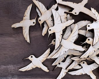 May include: A pile of wooden hummingbird cutouts, all facing the same direction. The cutouts are a light brown color and have a simple, elegant design.
