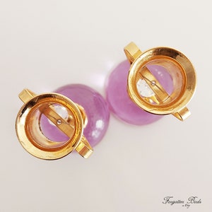 May include: Two small purple glass vases with gold tops and a clear crystal in the center of each.