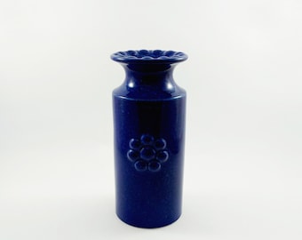 May include: A cobalt blue ceramic vase with a raised floral design. The vase has a rounded base and a slightly flared top.