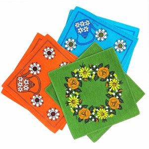 Könnte beinhalten: Vier Geschirrtücher, zwei orange mit einem Blumendesign und dem Wort "Sutta" und zwei blaue mit einem Blumendesign und dem Wort "Ulla", und ein grünes Geschirrtuch mit einem Blumengirlanden-Design.