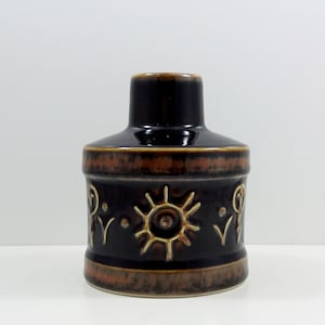 May include: A dark brown ceramic vase with a stylized sun design and other geometric patterns in a lighter brown glaze.