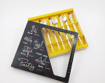 May include: A black and yellow box with a silver cutlery set inside. The box has a party theme with illustrations of activities like swimming, sailing, and picnicking. The text on the box reads "Party" and "Guldmeds AB Stockholm, C.A.B."