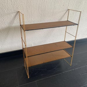 May include: A gold metal shelf unit with three shelves. The shelves are made of wood and are brown in color.