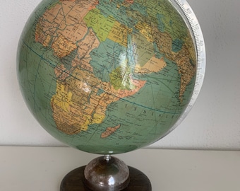 May include: A vintage green globe with a wooden base and a metal meridian. The globe features a detailed map of the world with country borders and major cities labeled.