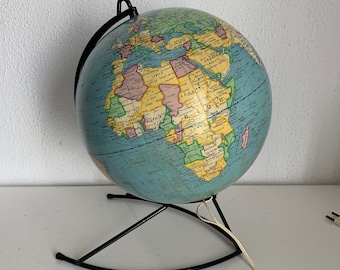 May include: A vintage illuminated globe with a light blue ocean and colorful continents. The globe is mounted on a black metal stand with a curved base and a black metal meridian. A white power cord extends from the base.