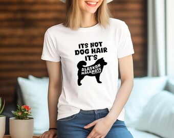 Pode incluir: Camiseta branca com texto preto que diz "Não é pelo de cachorro, é brilho de Alaskan Malamute". Abaixo do texto, há uma silhueta preta de um cão Alaskan Malamute.