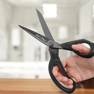 May include: Black scissors with a black handle and the text "David's Scissors" engraved on the blade. The scissors are being held by a hand.