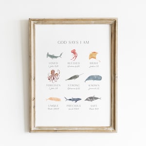 May include: Framed art print with a light wood frame. The print features watercolor illustrations of sea creatures and the words "GOD SAYS I AM" above the illustrations. Each illustration has a corresponding word such as "LOVED" and "BLESSED".