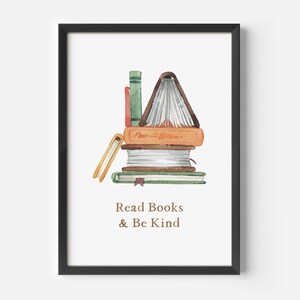 The image is a framed print with a watercolor illustration of a stack of books, accompanied by the text "Read Books & Be Kind" below the illustration.