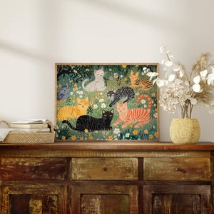 a picture of cats on a dresser with a vase of flowers