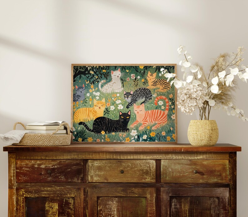 a picture of cats on a dresser with a vase of flowers