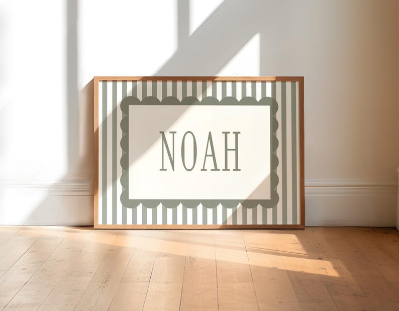 A framed picture with the word "NOAH" displayed on it, placed on a wooden floor against a white wall.