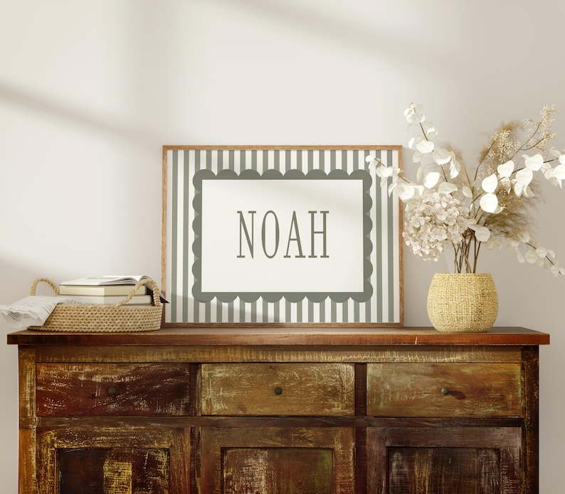 a wooden dresser with a framed sign that says "NOAH" on it, a woven basket, and a vase of white flowers.