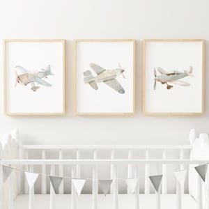 a baby's room with a crib and two pictures of airplanes