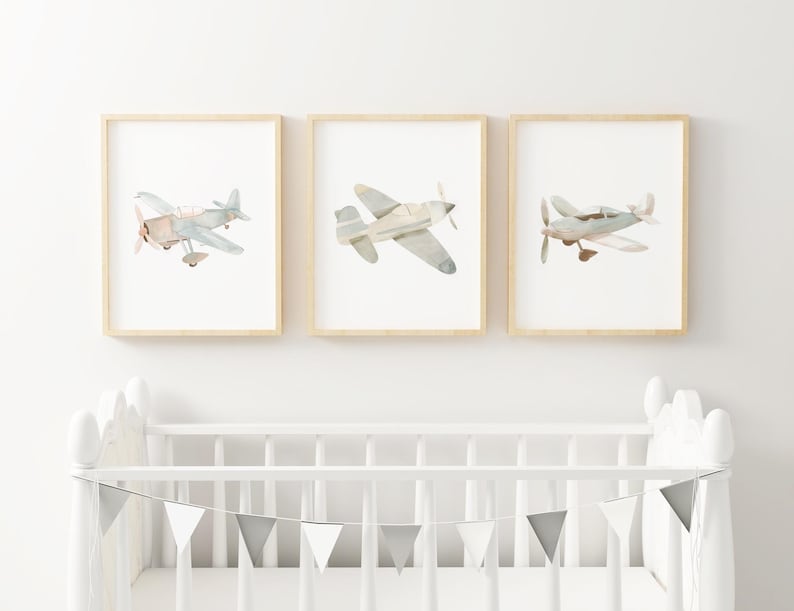 a baby's room with a crib and two pictures of airplanes