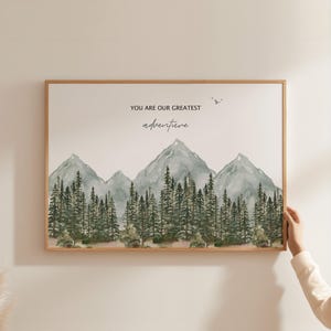 a person holding up a picture of a mountain