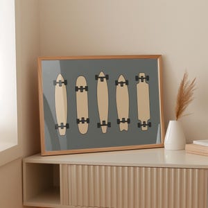 A framed artwork depicting five skateboards in a row, arranged on a shelf against a beige wall.