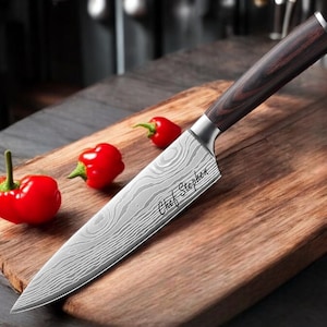 May include: A stainless steel chef's knife with a wood handle and a damascus blade. The knife is on a wooden cutting board with red peppers. The knife is engraved with the text "Chef Stephen".