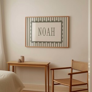 a bedroom setting with a bed, a wooden table, and a chair. Above the table, there is a framed picture with the word "Noah" written on it.