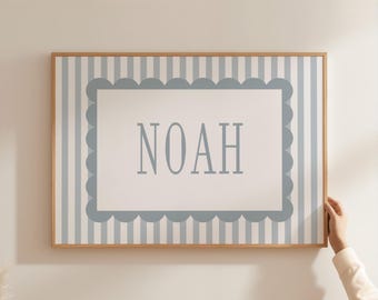 May include: A framed wall art piece featuring the name "NOAH" in a light blue font. The artwork has a white background with a light blue scalloped border and vertical stripes. The frame is made of wood.