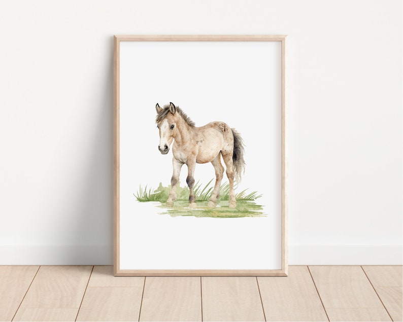 May include: A watercolor painting of a brown and white foal standing in a field of green grass.