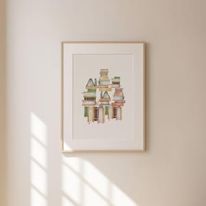 a framed artwork hanging on a wall, depicting a stack of books arranged in a visually appealing manner.