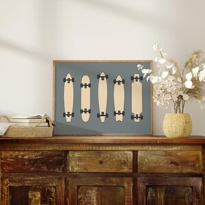 a wooden cabinet with a framed artwork of skateboards on top of it, along with a vase of white flowers and a stack of books.