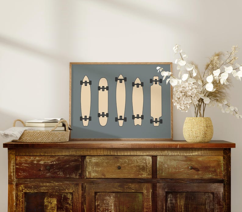 a wooden cabinet with a framed artwork of skateboards on top of it, along with a vase of white flowers and a stack of books.