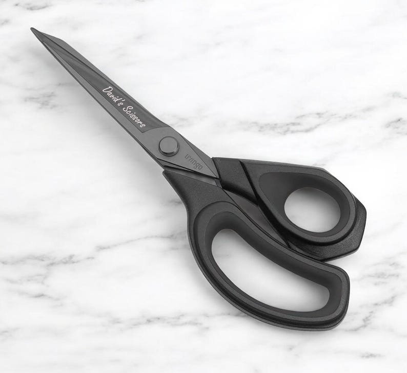 May include: Black scissors with a black plastic handle and a silver blade. The scissors have the text "David & Scissors" printed on the blade.