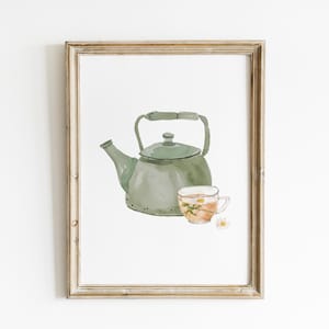May include: Watercolor print of a green teapot and a teacup with chamomile flowers. The artwork is framed in a light brown wooden frame, perfect for kitchen or dining room decor. The overall theme is tea and relaxation.