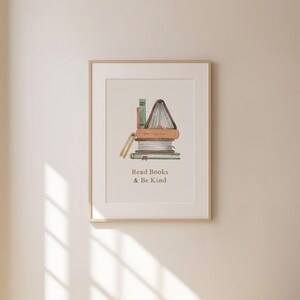 a framed print with a stack of books and the text "Read Books & Be Kind" written below it.