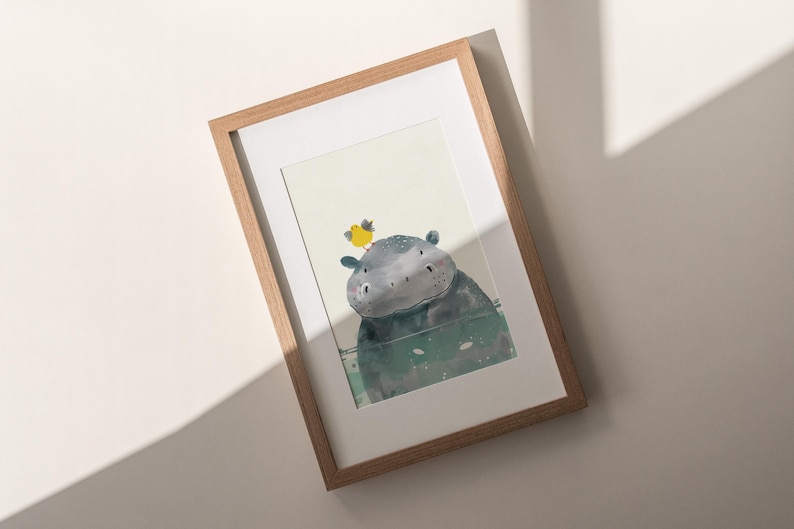 a framed artwork depicting a whimsical scene with a small, cartoonish creature, possibly a hippopotamus, sitting on a surface and looking up at the viewer.